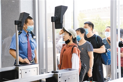 在西安火车站，旅客在工作人员指引下刷身份证进站乘车。记者 翟小雪 摄